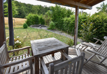 Wooden patio furniture on deck overlooking a garden, taken at Holiday home Magma 2 Persons in Germany.