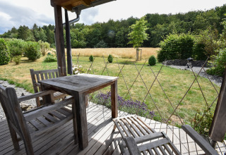 Houten terras met tuinset, uitzicht op grasveld en bomen bij Holiday home Magma in Duitsland.