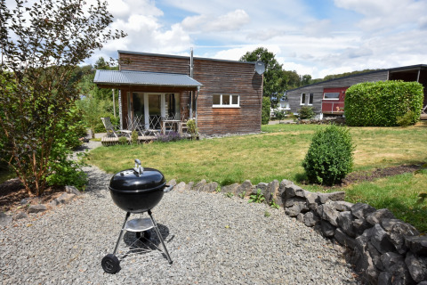 Udendørsbillede af feriehytte Magma til 2 personer i Tyskland, med en grill i forgrunden og have.