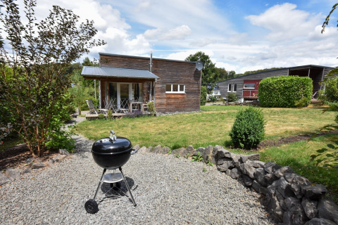 Havebillede af feriehus Magma 2 Persons i Tyskland, med grill og moderne træhuse i baggrunden.