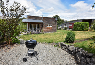 Tuinzicht bij vakantiehuis Magma 2 Persons in Duitsland, met barbecue en moderne houten chalets.