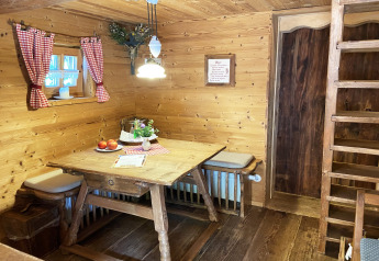 Cozy dining area in Almhütte chalet with wooden furniture, red checked curtains, and rustic charm.