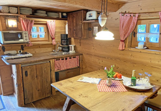 Gezellige chaletkeuken in Almhütte met houten meubelen, geruite gordijnen en landelijke uitstraling.