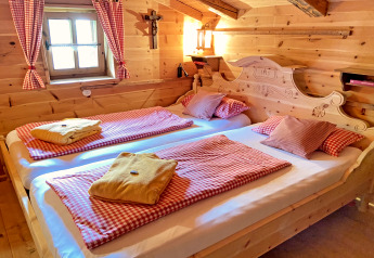 Cozy wooden bedroom in the Almhütte chalet in Germany with twin beds, red checkered bedding, and rustic decor.