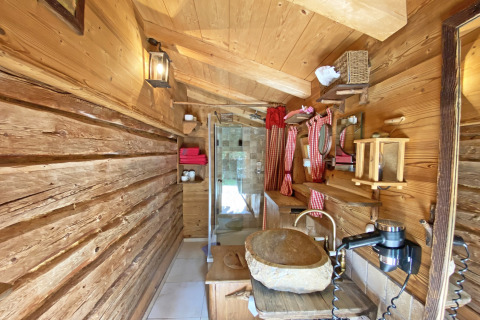 Rustieke houten badkamer in chalet Almhütte in Duitsland met stenen wasbak en roodgeruite gordijnen.