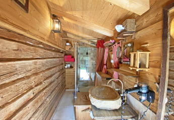 Rustic wooden bathroom at chalet Almhütte in Germany, featuring a stone sink and red checkered curtains.
