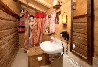 Woman at the shower in a rustic wooden bathroom, cozy chalet style, Almhütte, Germany, warmly lit.
