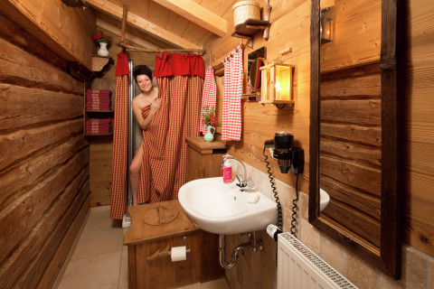 Vrouw bij de douche in een rustieke houten badkamer, gezellige chaletstijl, Almhütte, Duitsland.