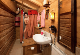 Vrouw bij de douche in een rustieke houten badkamer, gezellige chaletstijl, Almhütte, Duitsland.
