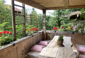 Rustic wooden bench and table with red flowers and garden view at the Almhütte chalet in Germany.