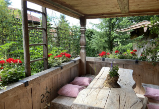 Rustieke houten tafel met rode bloemen en tuinuitzicht op de veranda van chalet Almhütte in Duitsland.