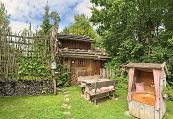Charming Almhütte chalet in Germany with wooden benches, cozy garden seating, and lush greenery.