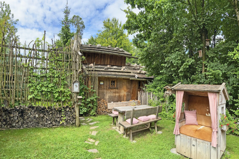 Sfeervol Almhütte-chalet in Duitsland met houten banken, tuinmeubilair en groene omgeving.