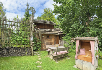 Charming Almhütte chalet in Germany with wooden benches, cozy garden seating, and lush greenery.