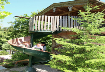 Due bambini e un adulto si divertono sullo scivolo a spirale presso lo chalet "Almhütte" in Germania.