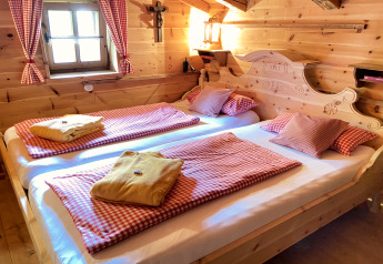Cozy bedroom in Almhütte chalet in Germany, wooden interior, checked bedding, and window.