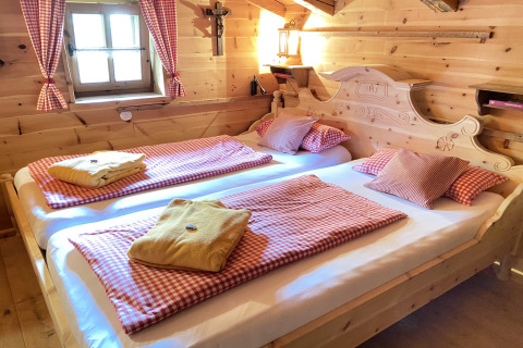 Gezellige slaapkamer in Almhütte chalet in Duitsland met houten interieur en geruit beddengoed.