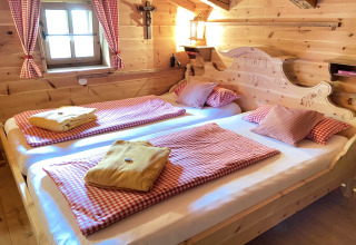 Gezellige slaapkamer in Almhütte chalet in Duitsland met houten interieur en geruit beddengoed.