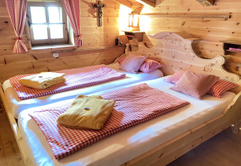 Cozy bedroom in Almhütte chalet in Germany, wooden interior, checked bedding, and window.