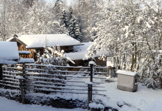 Verschneite Szenerie am Almhütte-Chalet in Deutschland mit Holzhütten und schneebedeckten Bäumen.