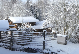 Besneeuwd winterlandschap bij chalet Almhütte in Duitsland met houten hutten en met sneeuw bedekte bomen.