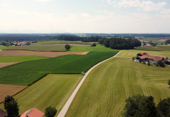 Vista panoramica di campi verdi, strada e chalét Almhütte immerso nella campagna.