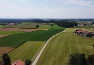 Landschapsfoto met groene velden, een weg en een Almhütte-chalet te midden van landbouwgrond.