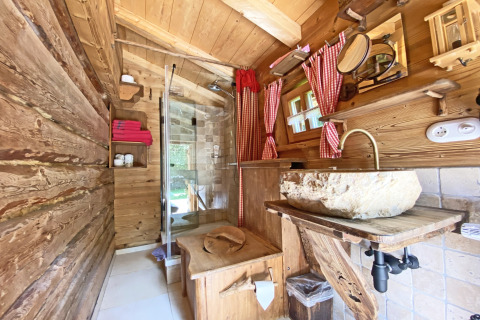 Rustieke houten badkamer bij het Almhütte chalet in Duitsland, met stenen wastafel en rode gordijnen.