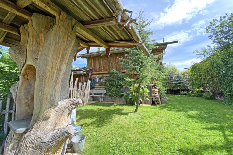 Gezellige Almhütte-chalet in Duitsland met houten balken, groene tuin en heldere blauwe lucht.