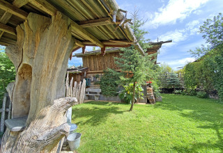 Gezellige Almhütte-chalet in Duitsland met houten balken, groene tuin en heldere blauwe lucht.