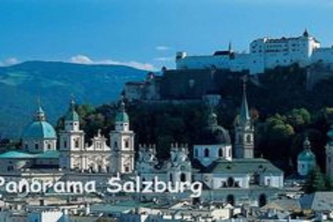 Panoramisch beeld van Salzburg met kerktorens en de vesting Hohensalzburg tegen een bergachtig decor.
