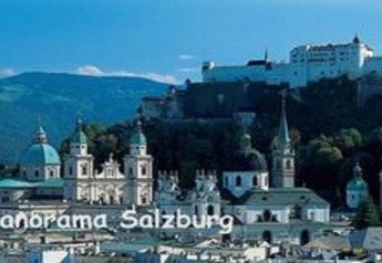 Panoramic view of Salzburg showing historic churches and the Hohensalzburg Fortress, mountains in the back.