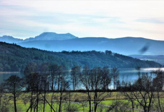 Uitzicht vanop chalet Almhütte in Duitsland met een meer, bergen, grasvelden en kale bomen vooraan.