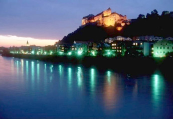 Vista serale di un castello illuminato su una collina vicino al fiume, da chalet Almhütte in Germania.