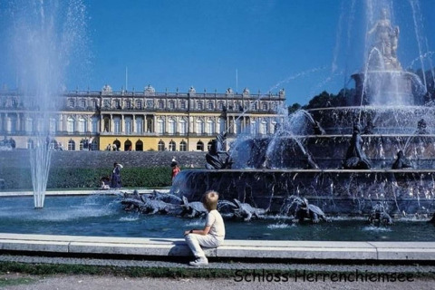 Fontein bij Schloss Herrenchiemsee in Duitsland met bezoekers en een schitterende barokke paleisgevel.