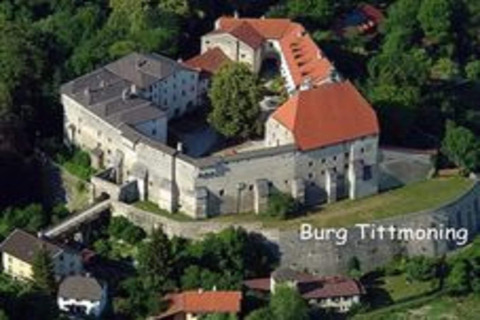Luchtfoto van het kasteel Burg Tittmoning in Duitsland, omringd door bomen en enkele huizen.