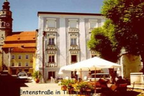 Foto van Entenstraße in Tittmoning, Duitsland, met historische gebouwen en een zonnig gelegen buitencafé.