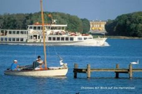 Uitzicht op de Chiemsee met boten en een veerboot bij Almhütte in Duitsland, paleis op de achtergrond.