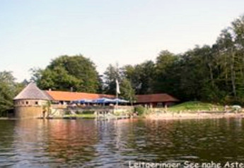 Chalet 'Almhütte' sul lago vicino ad Ascheberg, Germania, circondato da foresta, visto dall'acqua.
