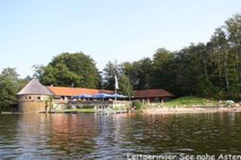 Chalet 'Almhütte' aan het meer bij Ascheberg, Duitsland, omgeven door bos, gezien vanaf het water.