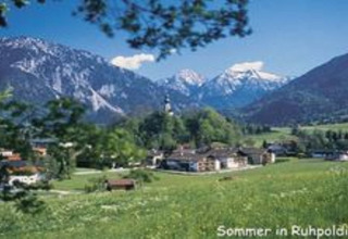 Zomeruitzicht vanaf chalet Almhütte in Ruhpolding, Duitsland, met groene weides en besneeuwde Alpen.