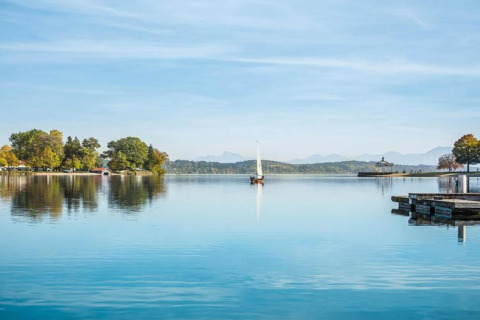 Zicht vanaf chalet Almhütte in Duitsland, met zeilboot op het meer en bergen op de achtergrond.
