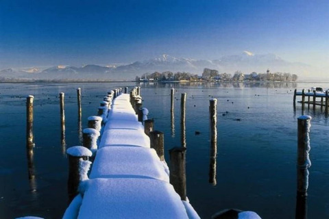Besneeuwde steiger leidt over een bevroren meer naar een eiland, bergen op de achtergrond in Duitsland.