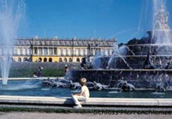 Fontana monumentale con il palazzo di Herrenchiemsee in Germania, giornata soleggiata con visitatori nel parco.