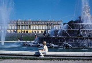 Grote fontein en paleis op de achtergrond bij Schloss Herrenchiemsee, Duitsland, mensen genieten van de zon.