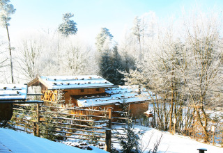 Chalet «Almhütte» in Duitsland, bedekt met sneeuw en omgeven door uitgestrekte besneeuwde bomen.
