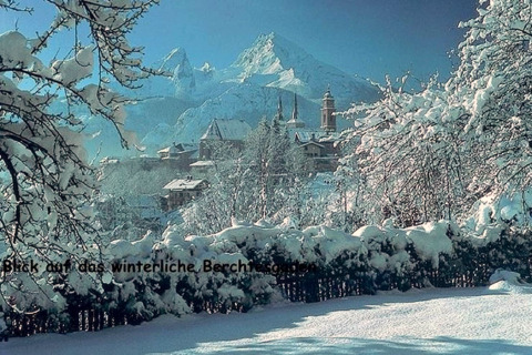 Winterlicher Ausblick von der Almhütte in Berchtesgaden, Deutschland, mit verschneiten Bäumen und Bergen.