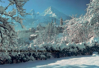 Winterlicher Ausblick von der Almhütte in Berchtesgaden, Deutschland, mit verschneiten Bäumen und Bergen.