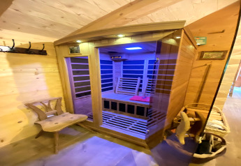 Wooden interior at a chalet named Almhütte in Germany featuring a modern glass infrared sauna cabin.