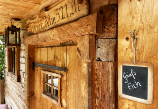 Almhütten-Eingang mit Holzschild 'Alm 521', Laterne und Tafel mit 'Griaß Eich' in Deutschland.